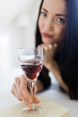 Attractive woman dressed in black sleepwear laying on bed - red wine