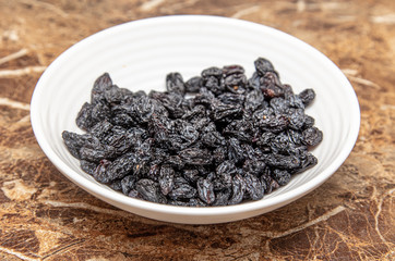 Black raisins in a plate on the table