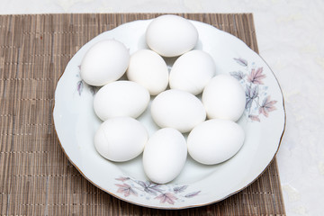 White chicken eggs in a plate on the table
