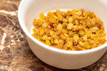 Yellow raisins in a plate on the table
