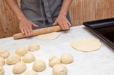Girl rolls the dough in the kitchen