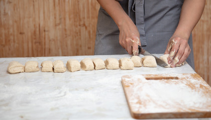The hostess cuts the dough in the kitchen