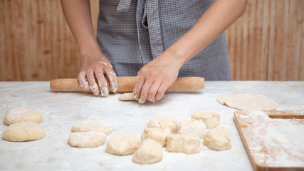 Girl rolls the dough in the kitchen