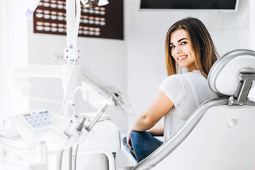 Pretty happy and smiling dental patient sitting in the dental chair at the dental office.