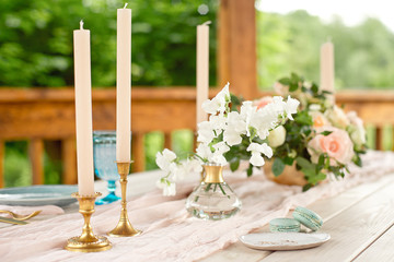 Decorated table for dinner for two person, with plates knife, fork, cheese, wine, wine glasses and flowers in a copper vase.