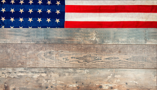 American flag lying on an aged, weathered rustic wooden background.