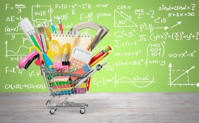 Stationery objects in mini supermarket cart on wooden desk