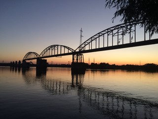Fototapeta na wymiar old military bridge over river at sunset