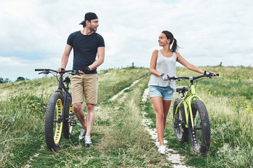 Young man looks at young beautiful woman with fatbike