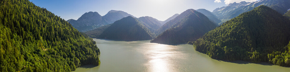 Aerial photography. Attraction of Abkhazia lake Ritsa. High mountains, green trees, wildlife, clear mountain water. Panoramic picture. Blue sky. High in the mountains.