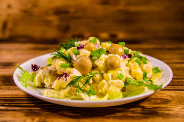 Salad with marinated mushrooms, eggs, red onion, boiled potato and mayonnaise on wooden table