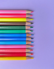 top view on colorful pencils in line on mauve background