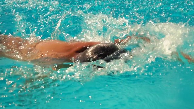 Boy swims in the style of crawl in the pool.