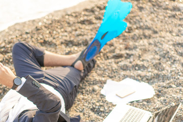 Business man in a business suit relaxing on the beach in flippers