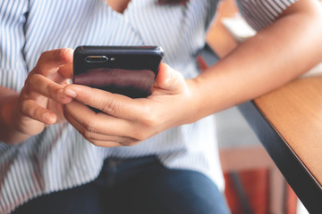 Woman typing text message on smart phone in a cafe.