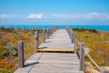 The wooden stairway at the rocky seashore on a sunny day. Polvoeira the beach. Pataias, Portugal, Europe