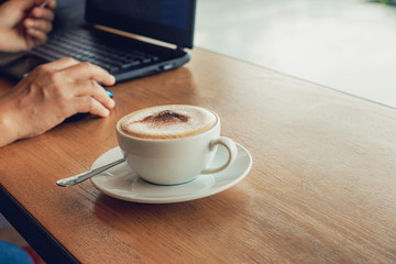 Freelancer working in cafe on a wooden counter bar with coffee mugs and laptop.