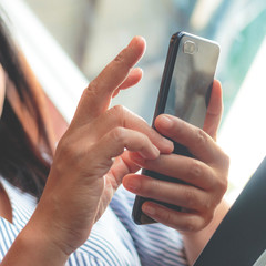Woman typing text message on smart phone in a cafe.