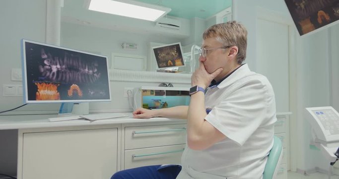 Dentist with teeth x-ray on screen