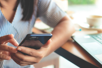 Woman typing text message on smart phone in a cafe.