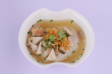 Vietnamese Rice Noodles Soup with pork spare ribs holding in fork and Vietnamese style sausage, deep fried red onion and parsley on wooden table background, popular delicious Vietnamese food