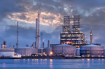 Obraz na płótnie Canvas Petrochemical industry next to a river with a dramatic cloudy sky at twilight, Port of Antwerp, Belgium.