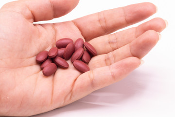 Ferrous Fumarate pills with Vitamins for treat iron deficiency anemia in hand on white background.