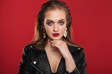 Image of gorgeous young woman 20s with bright makeup wearing earrings and leather jacket posing at...