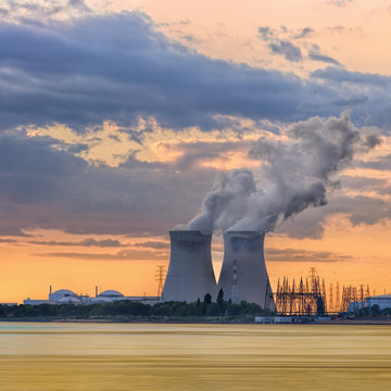 Riverbank with nuclear power plant Doel during a sunset with dramatic cluds, Port of Antwerp, Belgium