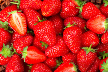 Juicy washed strawberries in wooden bowl on kitchen table.