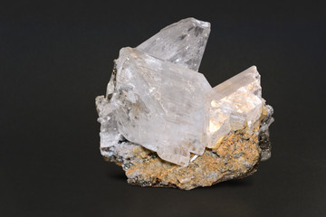 Group of large, clear gypsum crystals on a dark background.