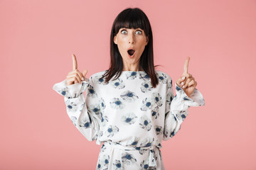 Shocked young woman posing isolated over pink wall background pointing.