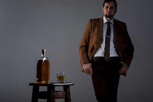 Male silhouette in the dark and a bottle and whiskey glass on dark grey background