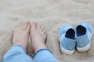 Fototapeta premium feet on the sand and a pair of shoes