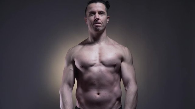 Muscular young man is posing with no shirt on, 4k