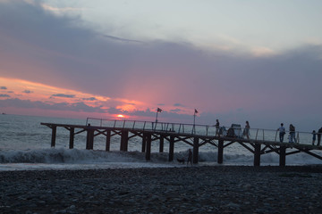 Obraz premium over Batumi beach Jetty, as powerful waves roll in, and a very colorful sky is reflected on the beach. sunset on the city embankment