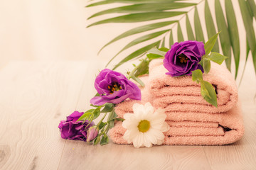 Obraz na płótnie Canvas Stack of soft terry towels with flowers on wooden boards