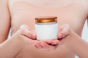 cropped view of teenage girl holding cosmetic cream in hands