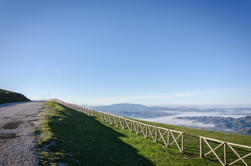 Fototapeta na wymiar View of Landscape and Mountains from Mt. Cucco - Gubbio, Italy with Fence and Fog