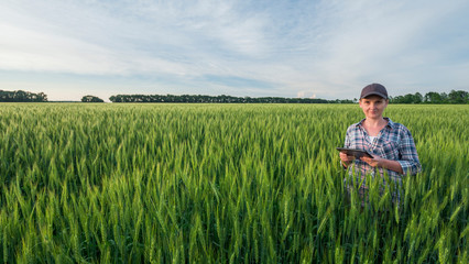 Portrait of a female farmer with a tablet in hand. Standing in the middle of a wheat field.