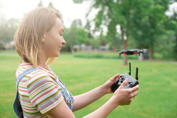 The girl drives a quadrocopter in the park. Flights in the park. Fun spending time