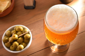 Glass beer with appetizer on wooden table top view detail
