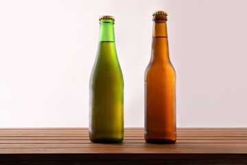 Two different beer bottles filled and closed on wooden table
