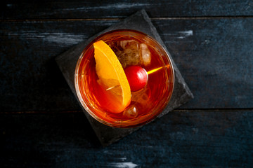 Whiskey and Cola with ice and citrus classic cocktail on dark wooden background