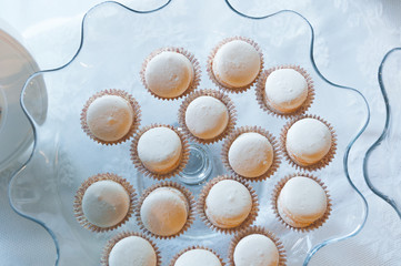 Tasty white mini cakes on a glass curved plate. Top view.