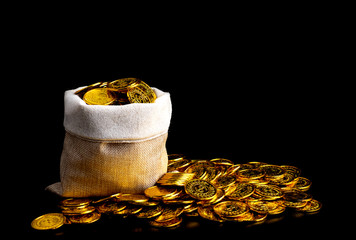 Stacking gold coin in treasure sack on black background