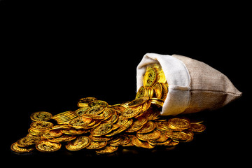 Stacking gold coin in treasure sack on black background