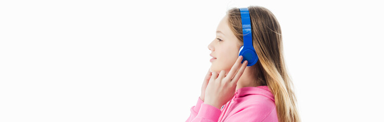 Naklejka premium side view of teenage girl touching headphones on head isolated on white, panoramic shot