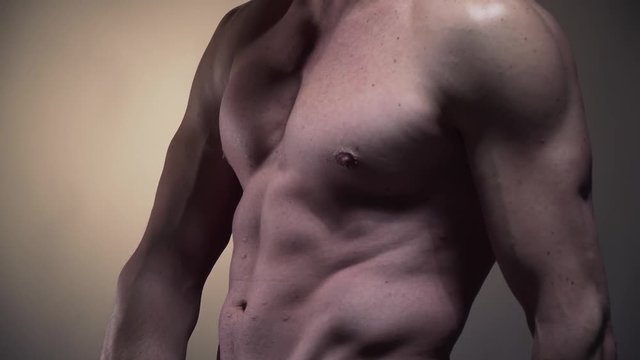 Close up of the buff mans abs, posing in the studio in 4k