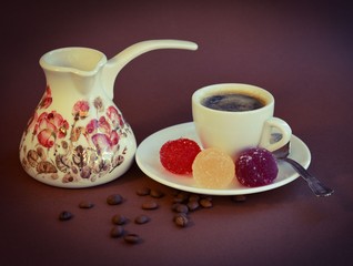 Fragrant Turkish coffee with marmalade balls and scattered coffee beans on a brown background